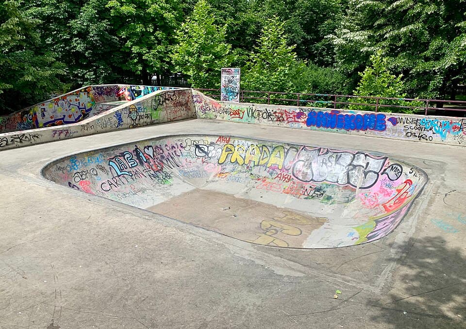 An empty concrete skate park bowl covered in graffiti