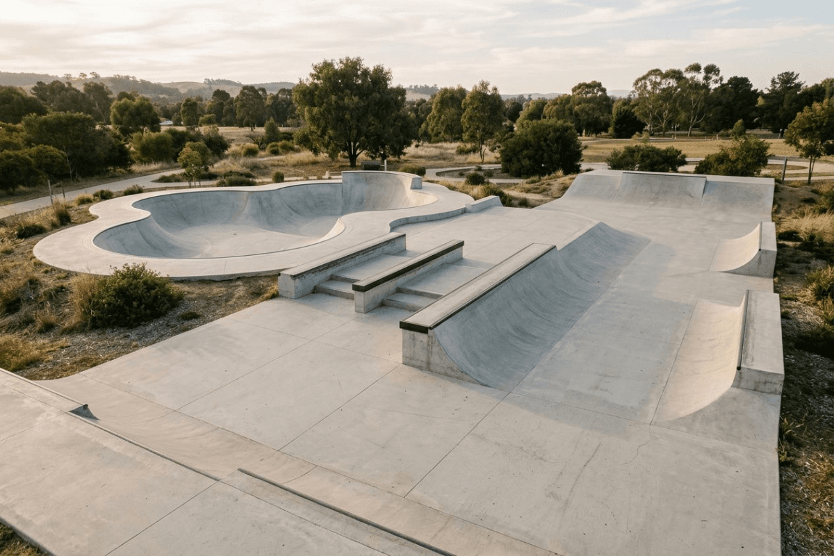 Overhead view of a concrete skate park showing a bowl, low ledges, a rail, and a bank ramp
